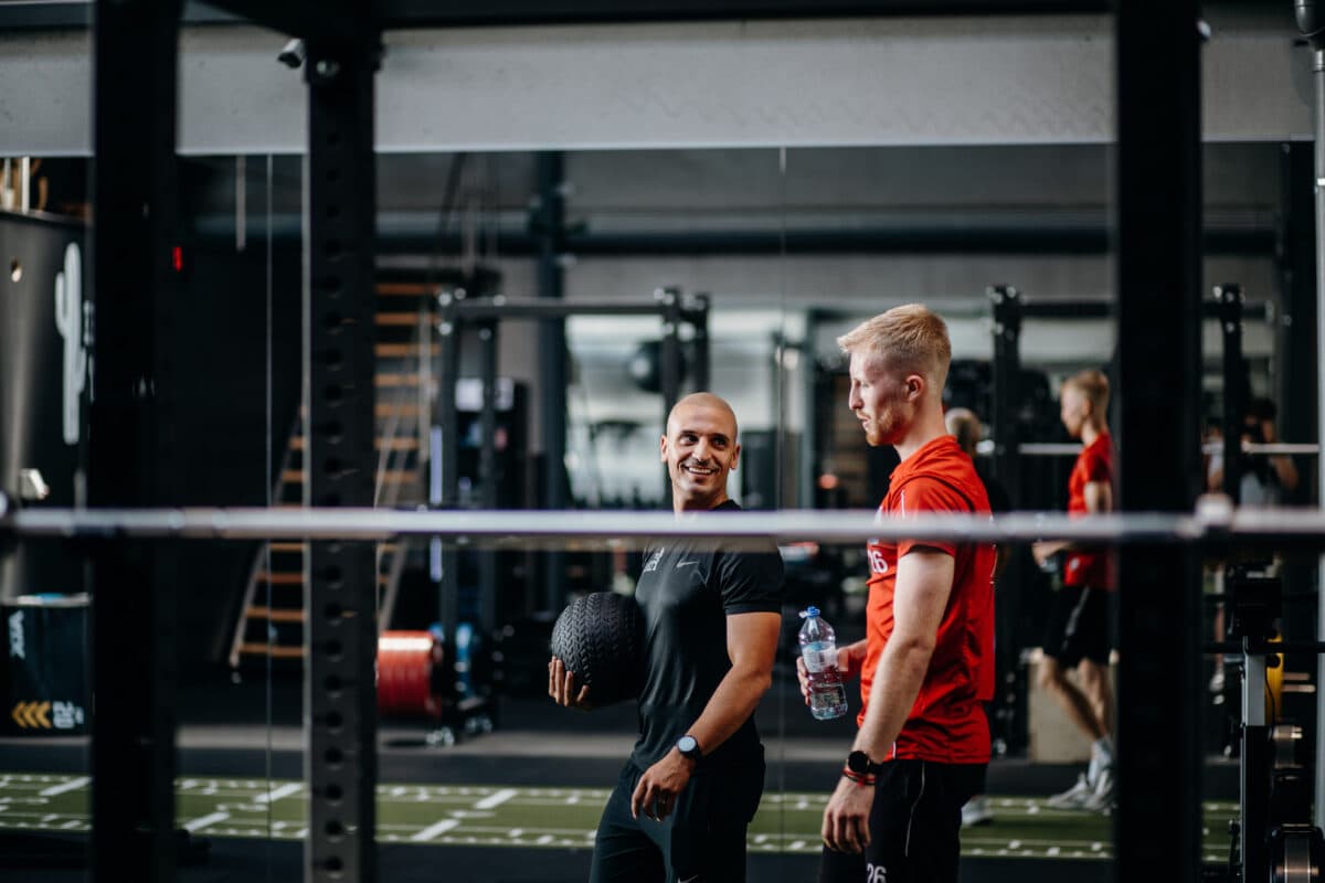 Performance trainer samen met professioneel voetballer in de fitness tijdens een oefening